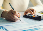 A person fills out the 1040 tax form, with the help of a calculator
