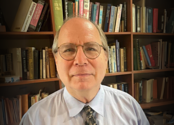 Picture of David Beito in front of bookcase.