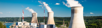 Three nuclear power plant 'cooling stacks' billowing steam are pictured next to a river. 