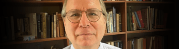 Picture of David Beito in front of bookcase.