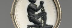 A medallion with the image of a kneeling, chained black man with clasped hands surrounded by the words "Am I not a man and a brother?"