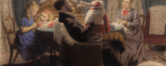 A family sits around a table. A child sits in her father's lap, arms outstretched.